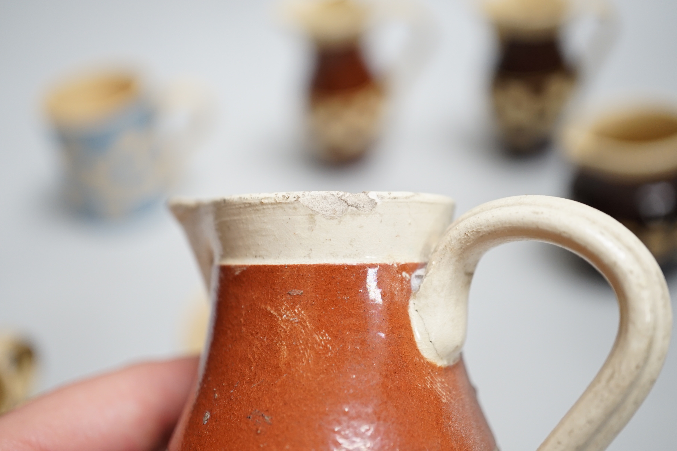Eight 19th century slip-decorated creamware chequer-pattern jugs and mugs, tallest 10cm